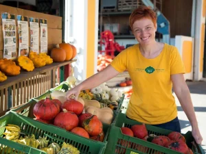 Karin Metz vom Bio-Kürbishof Metz im Mostviertel mit Kisten voller Speisekürbisse vor dem Hofladen