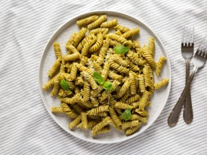 Fusilli mit Kürbiskernpesto und Basilikum auf einem Teller